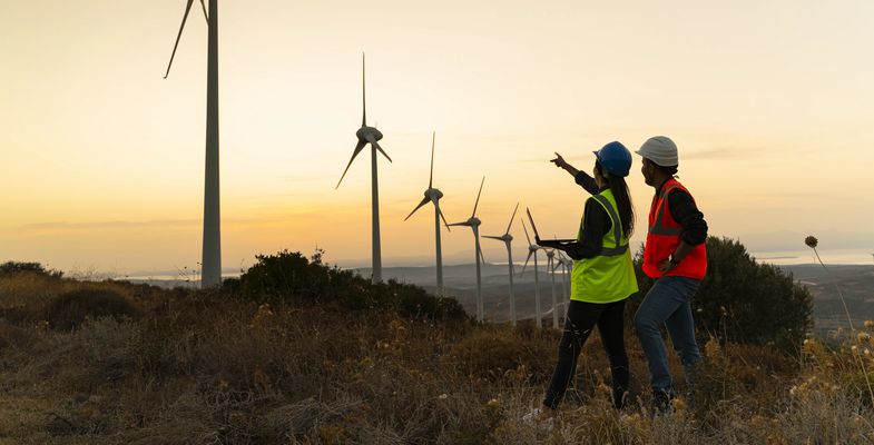maintenance engineer team working in wind turbine farm at sunset